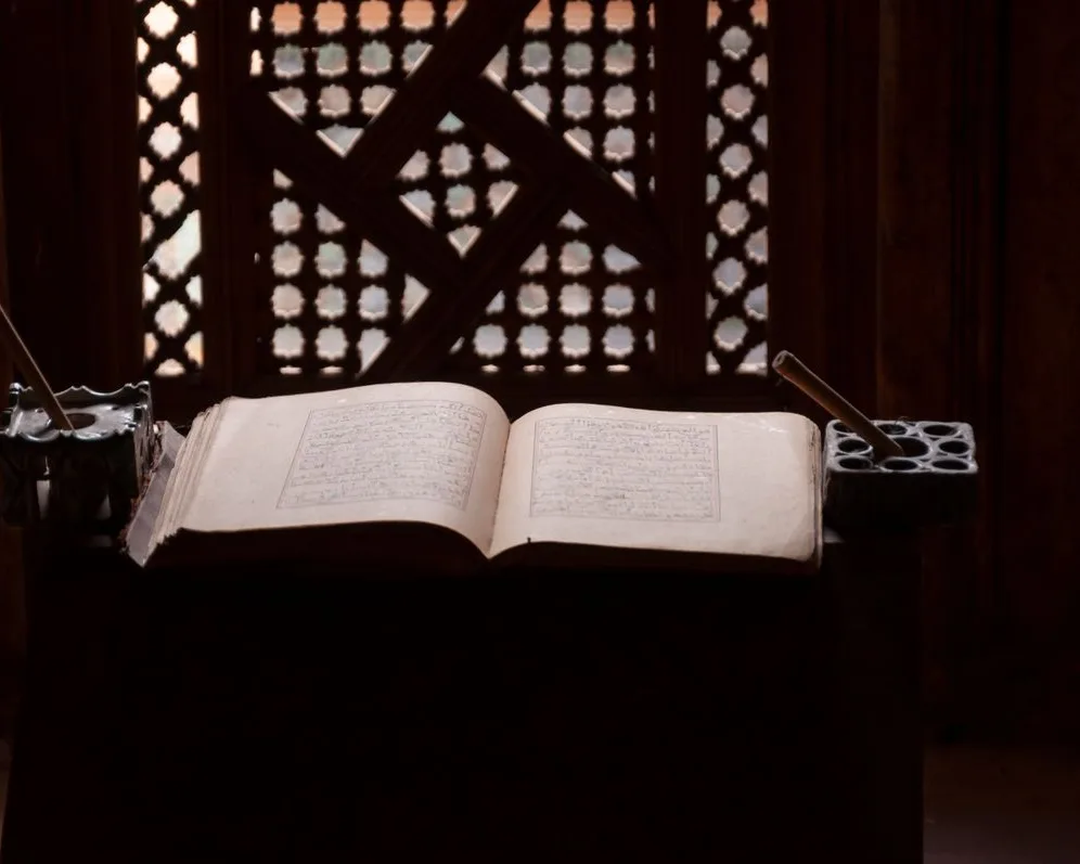 An open handwritten kitab on a rehal in a madrasah study room